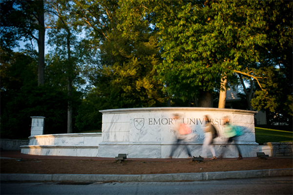 sign for Emory University with students walking past it