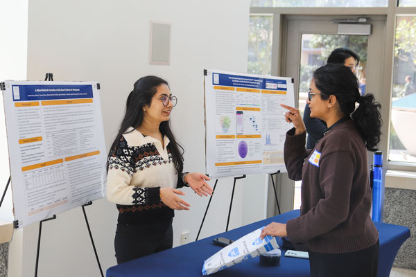 a woman in front of two presentation panels speaking with another woman