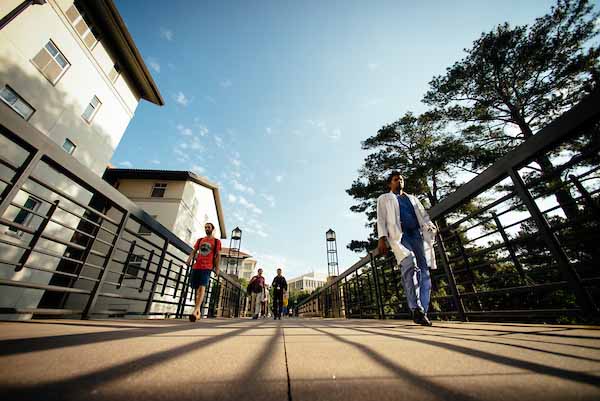 People walking across a bridge on the Emory Atlanta campus