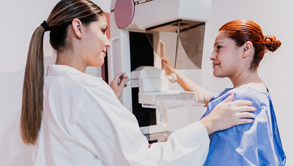 Woman and health care worker in front of mammogram machine.