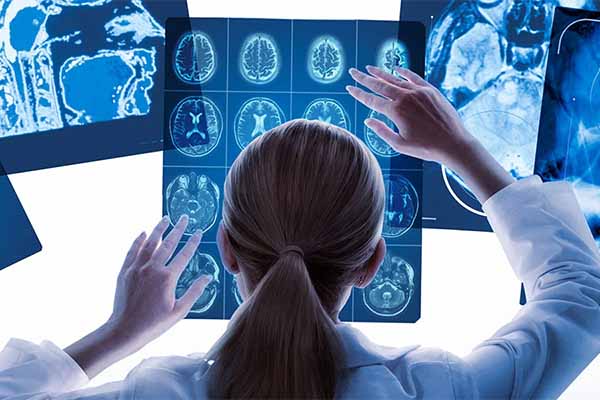 Person in a lab coat viewing x-rays on a light table