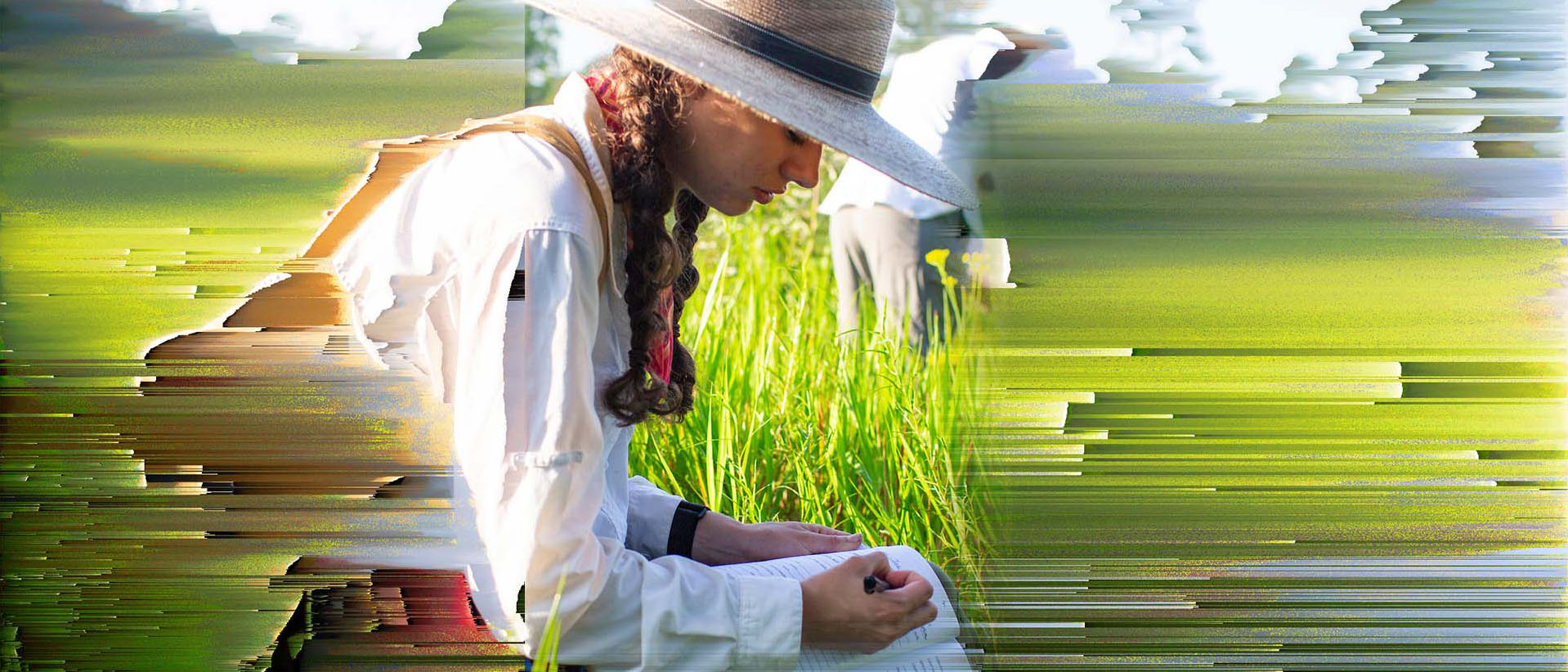 woman writing on a notebook in a field