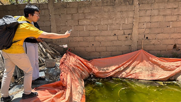 Xiao Huang records the GPS coordinates for a construction site cistern containing algae. Huang is focused on aspects of the project involving AI, remote sensing and satellite-image processing.